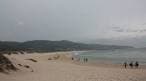 Playa de Doniños con bañistas y cielo nublado
