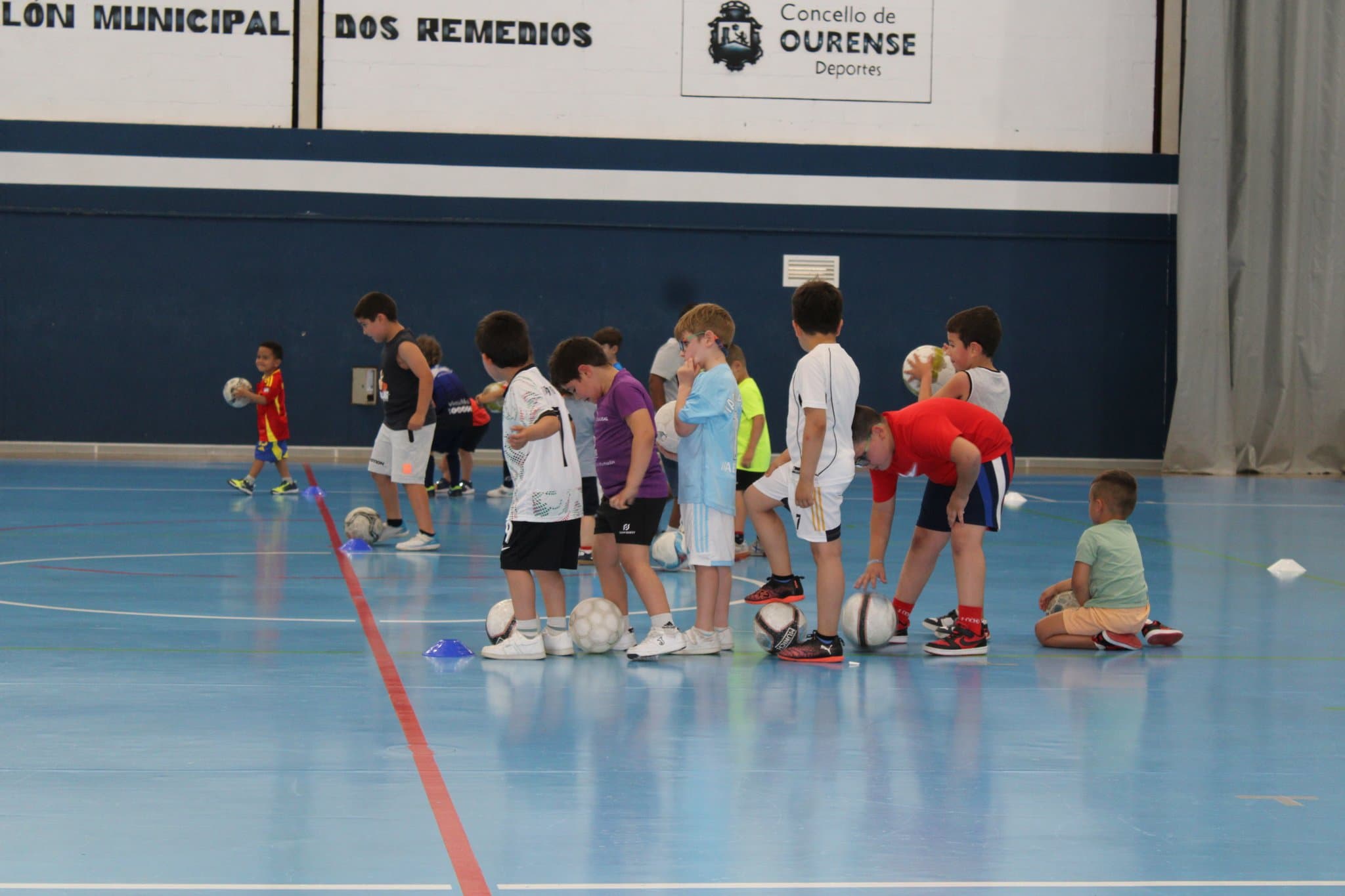 Niños practicando deporte en la cancha azul del Pabellón dos Remedios