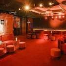 Zona de lounge de Don Giorgio con asientos y mesas bajas en ambiente rojizo