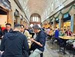 Zona de restauración interior del Mercado de Abastos con mesas y comensales
