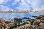Costa rocosa de la Ensenada del Orzán con reflejos de la ciudad en el agua