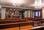 Capilla o salón de actos con bancos de madera y candelabros