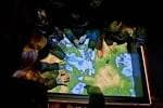 Visitantes interactuando con una mesa táctil de mapas