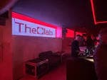 Interior de The Clab con iluminación roja y pantalla con el logo