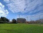 Amplia zona verde del Parque de Tafisa con edificios en construcción al fondo