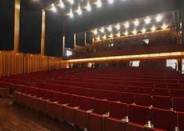 Interior del auditorio con butacas rojas y escenario vacío