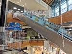 Interior del centro comercial con escaleras mecánicas y tiendas