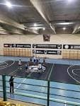 Interior del polideportivo con cancha, gradas y marcador electrónico