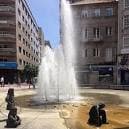 Vista general de la Fuente de los Niños con altos chorros de agua en un día soleado