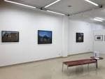 Sala de exposición de la Galería Marisa Marimón con cuadros y banco de descanso