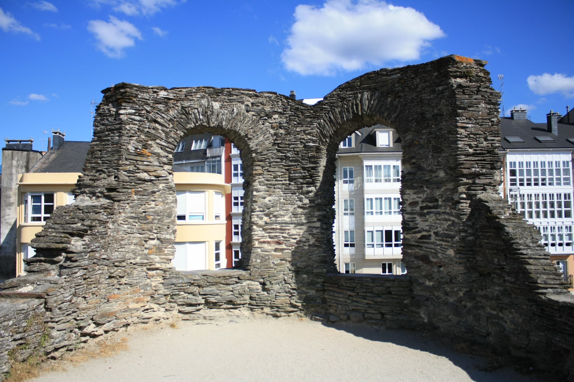 Muralla Romana de Lugo con aperturas y edificios al fondo