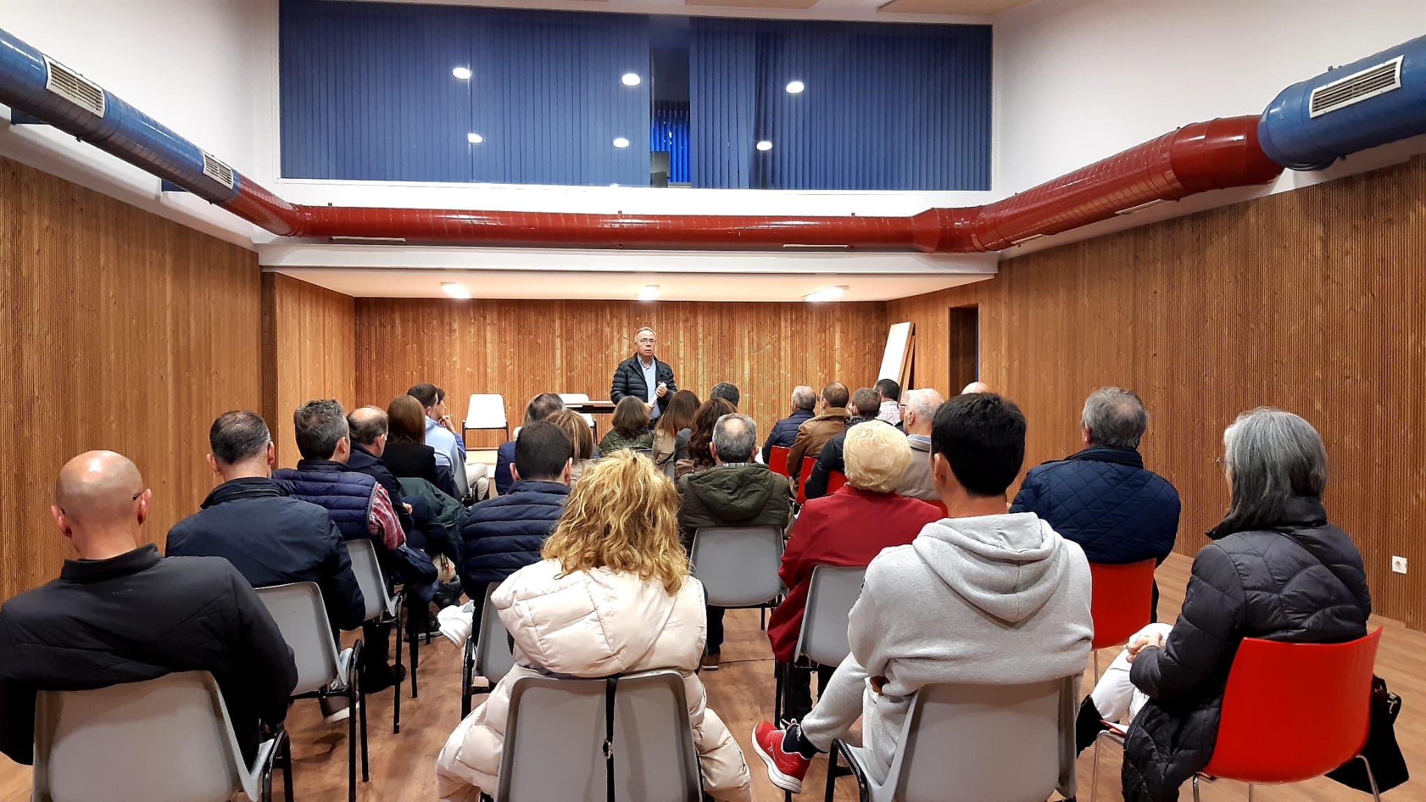 Interior de sala de eventos con público y orador