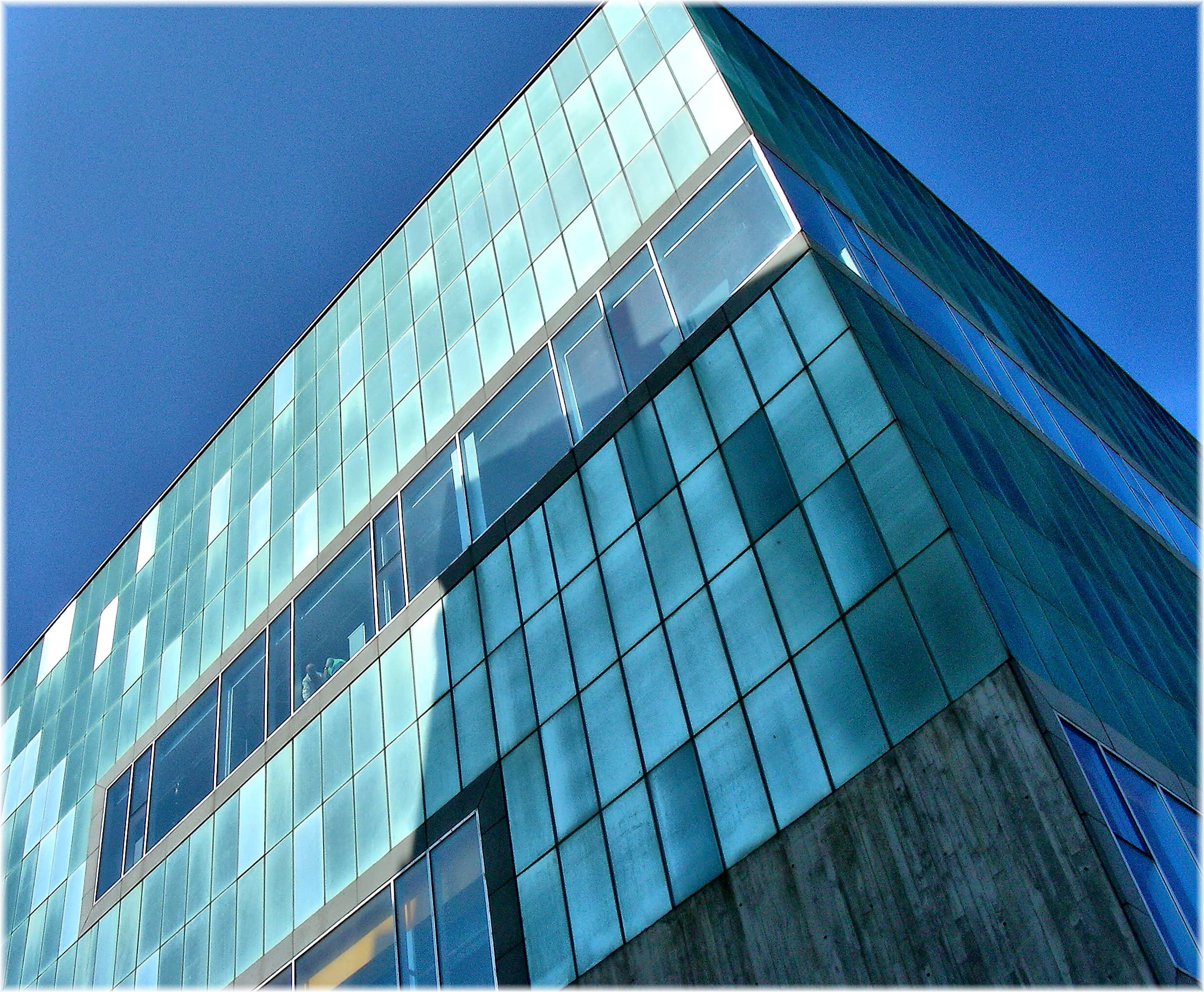 Vista angular de la fachada de cristal del MUNCYT bajo un cielo azul