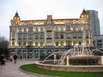 Fachada iluminada del edificio Casa Conde (Banco Herrero) y la fuente de la plaza al anochecer