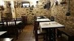 Salón rústico de un restaurante con paredes de piedra y mobiliario de madera en Vigo