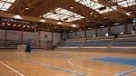 Interior del pabellón deportivo principal con cancha de madera y gradas