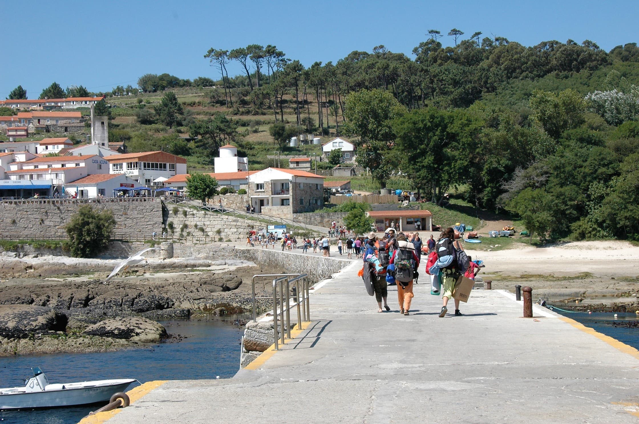 Vista del muelle y el pueblo de Isla de Ons con personas desembarcando