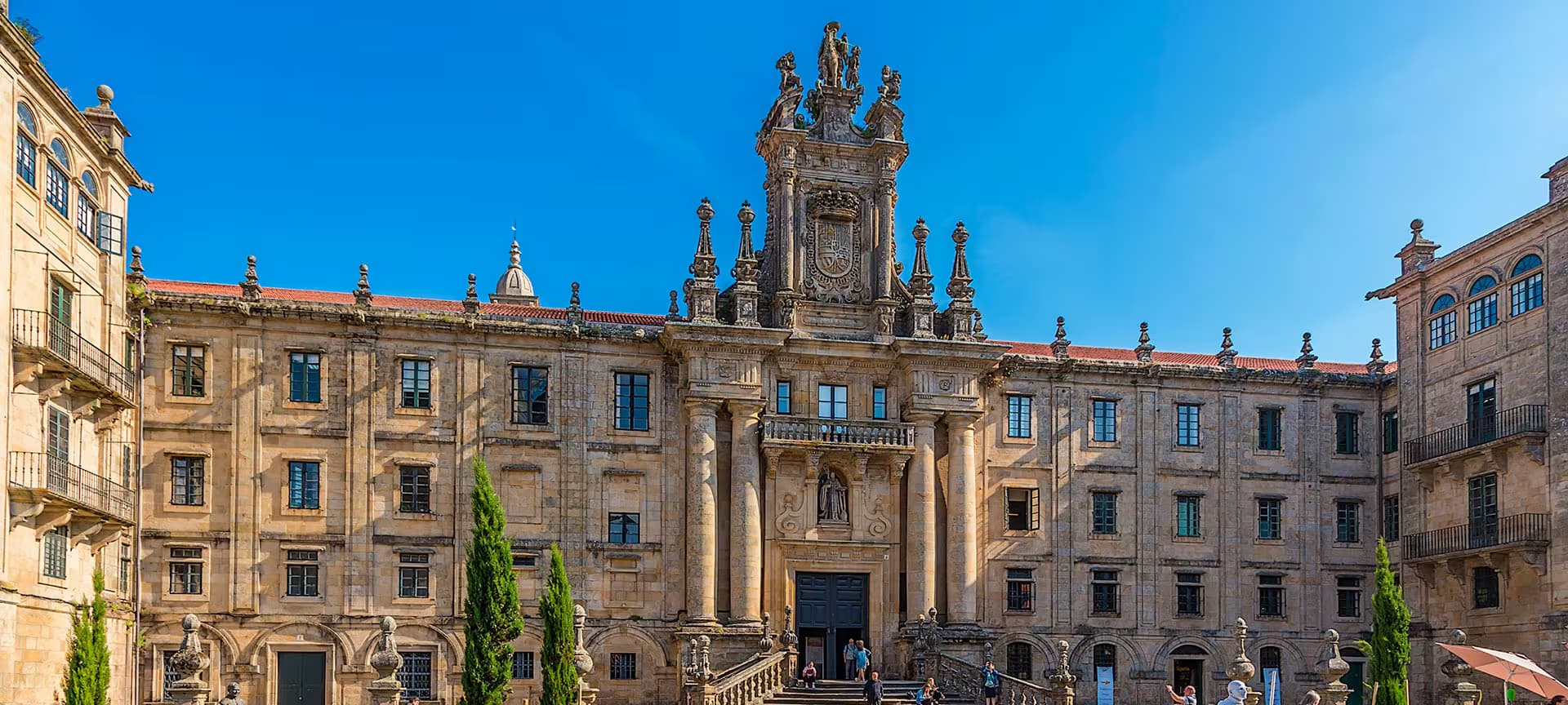 Fachada principal del Monasterio de San Martiño Pinario con jardines bajo cielo azul