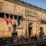 Entrada monumental del Hostal dos Reis Católicos con banderas en la Praza do Obradoiro