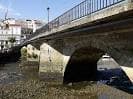 Perspectiva inferior de los arcos de piedra del Puente Viejo de Betanzos sobre el río