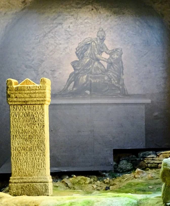 Primer plano de un pilar antiguo con una estatua al fondo