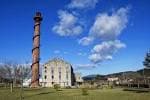 Vista exterior de la Azucreira de Portas con su chimenea y edificio principal bajo un cielo azul