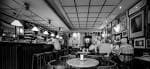 Amplia vista interior en blanco y negro del salón principal del café