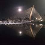 Puente de los Tirantes de noche con la luna llena reflejada en el agua