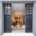 Entrada principal del local con puertas de madera oscura y mesa exterior