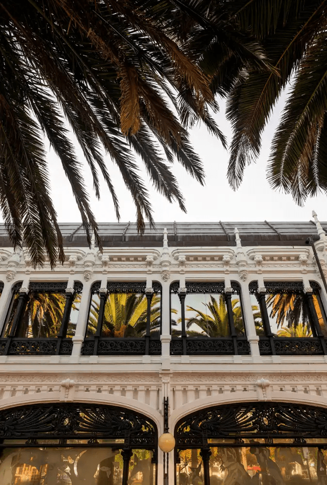 Detalle de la fachada superior del Kiosco Alfonso con palmeras
