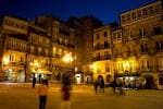 La Praza da Constitución iluminada por la noche, con edificios históricos y ambiente nocturno