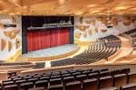 Escenario del auditorio principal con telón rojo y butacas vacías