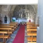 Interior de la Capilla de San Roque con bancos de madera y alfombra roja.