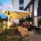 Vista de la terraza exterior del hotel con mesas y sillas, bajo grandes sombrillas.