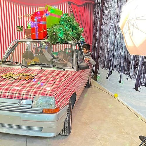Interior de sala de arte con decoración festiva y un coche antiguo