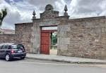 Entrada de piedra con portón de madera a un recinto en Santa Comba