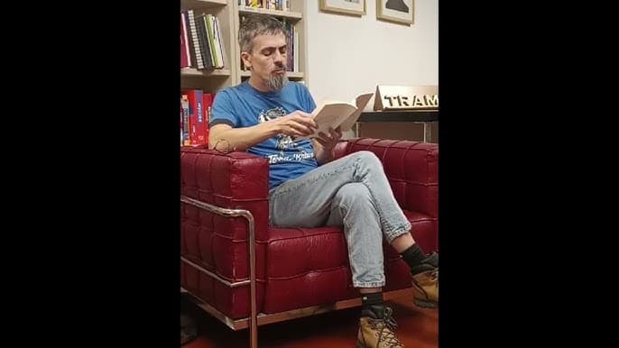 Hombre sentado en un sillón rojo durante una presentación de libro en la librería