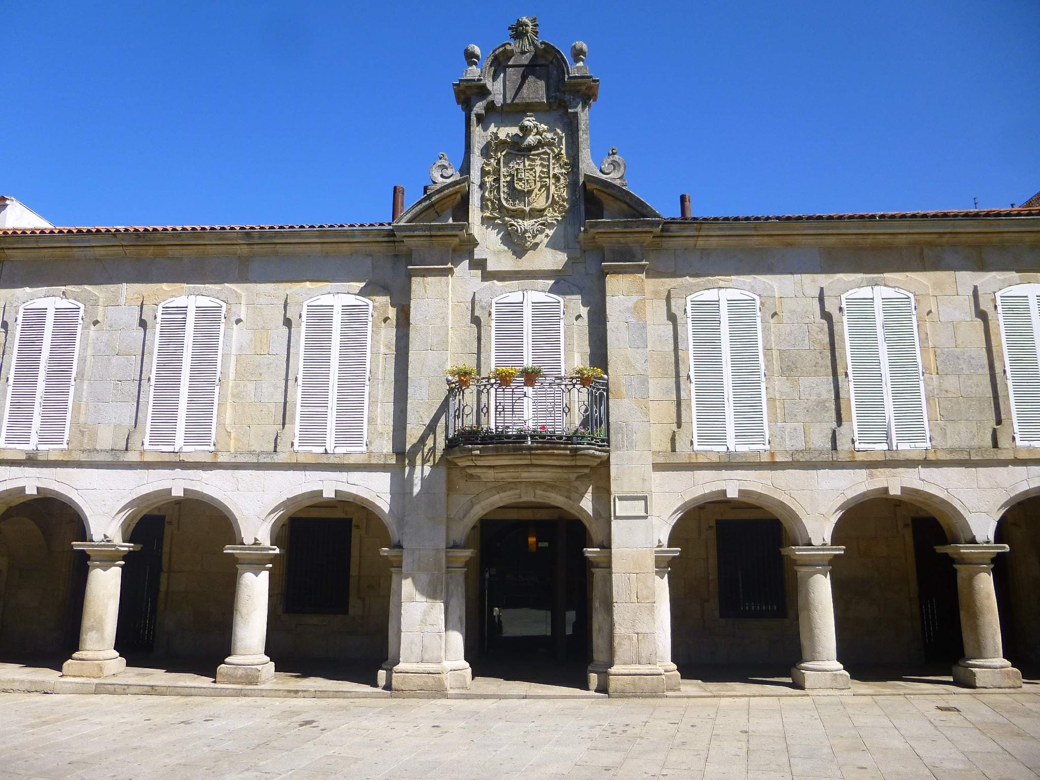 Fachada principal del Pazo de Mugartegui con arcos y escudo.