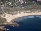 Playa curva de Doniños desde el aire con zona urbana cercana
