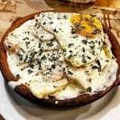 Plato de huevos rotos con patatas y salsa en cazuela de barro