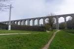 Viaducto de A Chanca visto desde un sendero, con pilares y arcos de piedra.