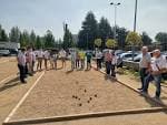 Grupo de personas reunidas en un campo de petanca con bolas en el suelo