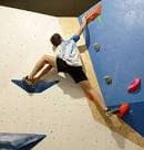Deportista escalando una pared de búlder en un rocódromo