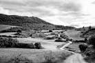 Paisaje rural en blanco y negro con campos y caminos en la región de Ourense