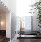 Patio interior o sala con mesa larga, bancos y paredes con diseño geométrico