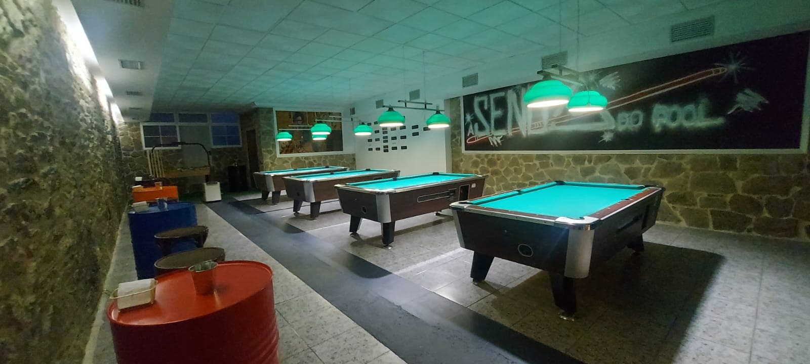 Interior de A Senda do Pool con varias mesas de billar y ambiente iluminado en tonos verdes