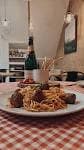 Plato de espaguetis con albóndigas y botella de vino en mesa con mantel de cuadros