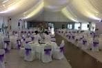 Salón de eventos decorado para celebración con mesas y sillas vestidas