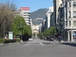 Vista longitudinal de la Calle Uría, avenida arbolada con edificios y la montaña de fondo