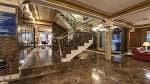 Gran vestíbulo del hotel con escalera de mármol y barandilla dorada